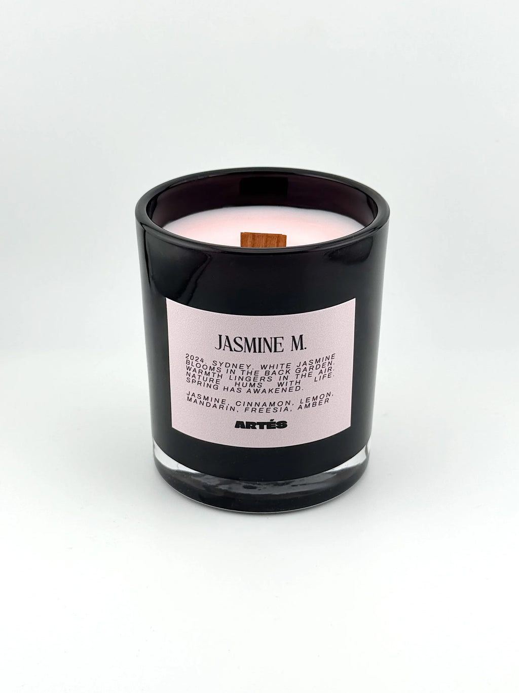 Candle in a black container with a pink label on a white background