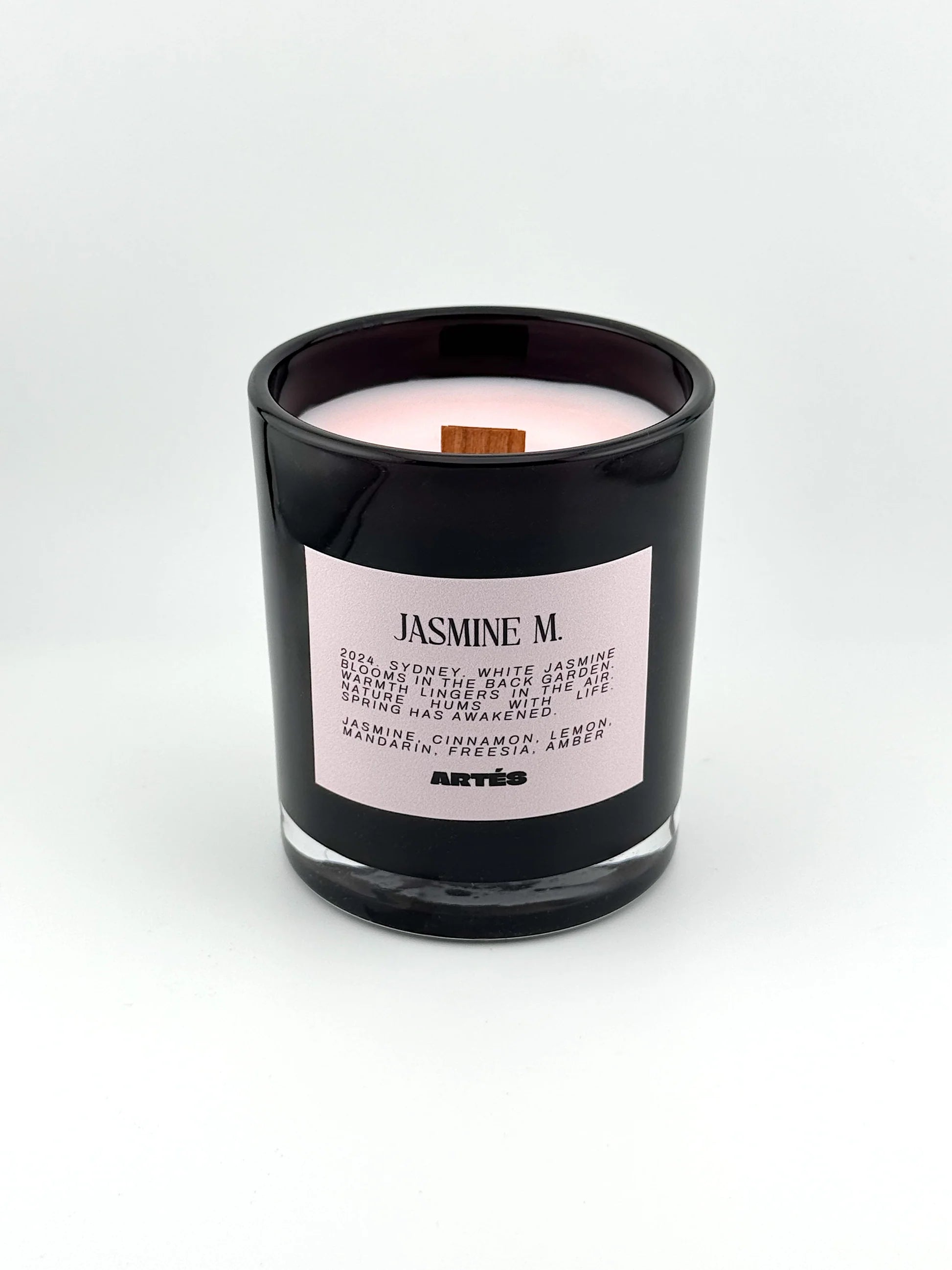 Candle in a black container with a pink label on a white background