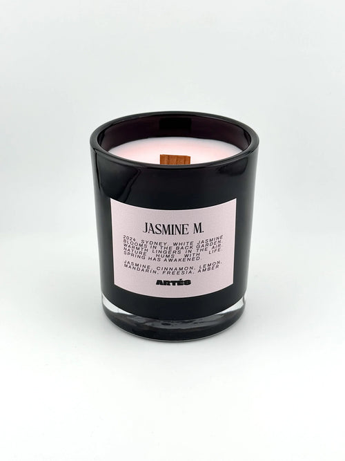 Candle in a black container with a pink label on a white background
